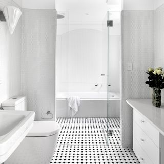 An all-white bathroom with graphic, black and white tiles