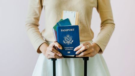 picture of woman holding a U.S. passport and an airplane boarding pass