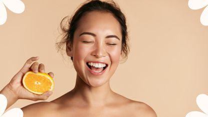 woman with beautiful skin squeezing an orange as we discuss how to use vitamin C serum