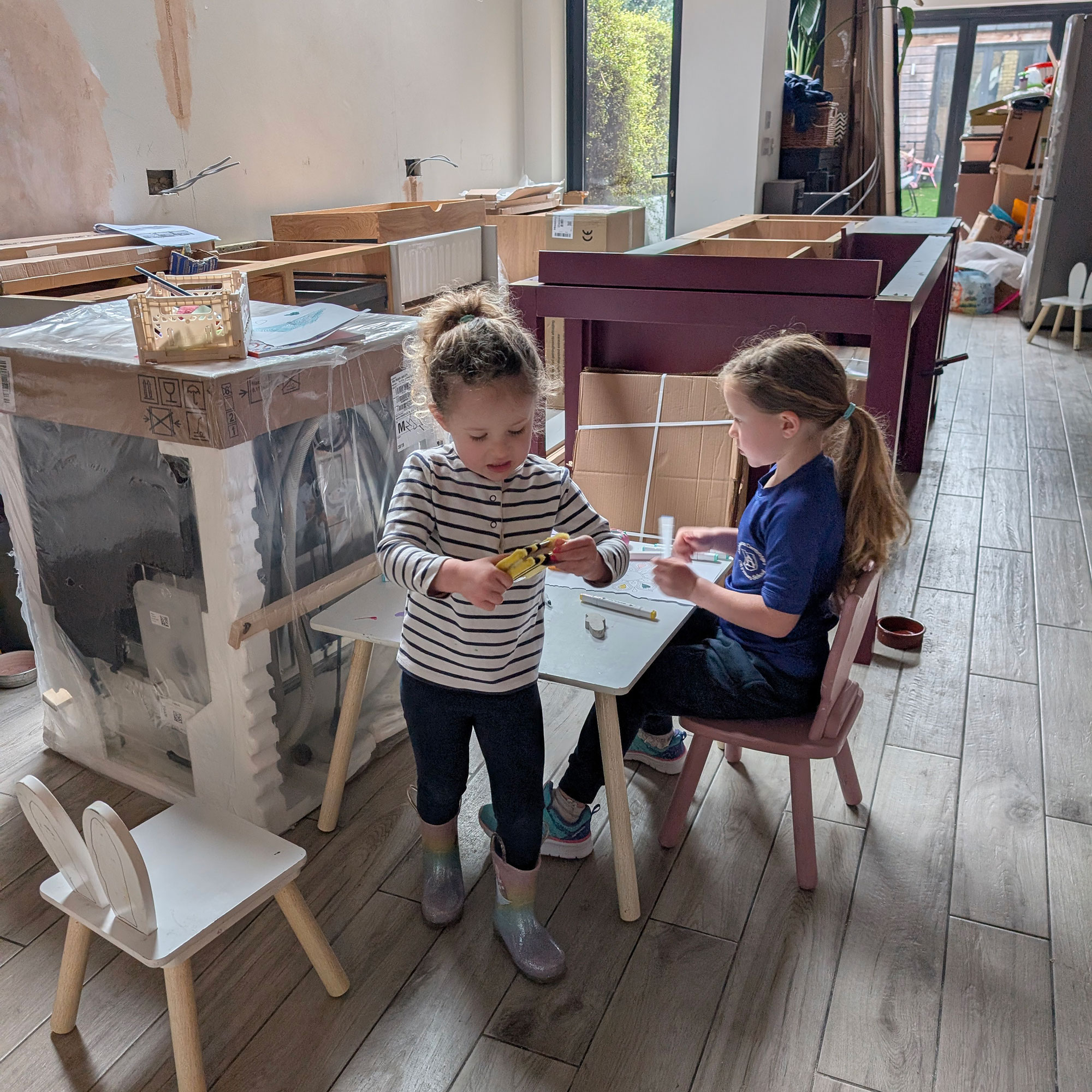 Two small girls playing at table in kitchen mid-renovation process