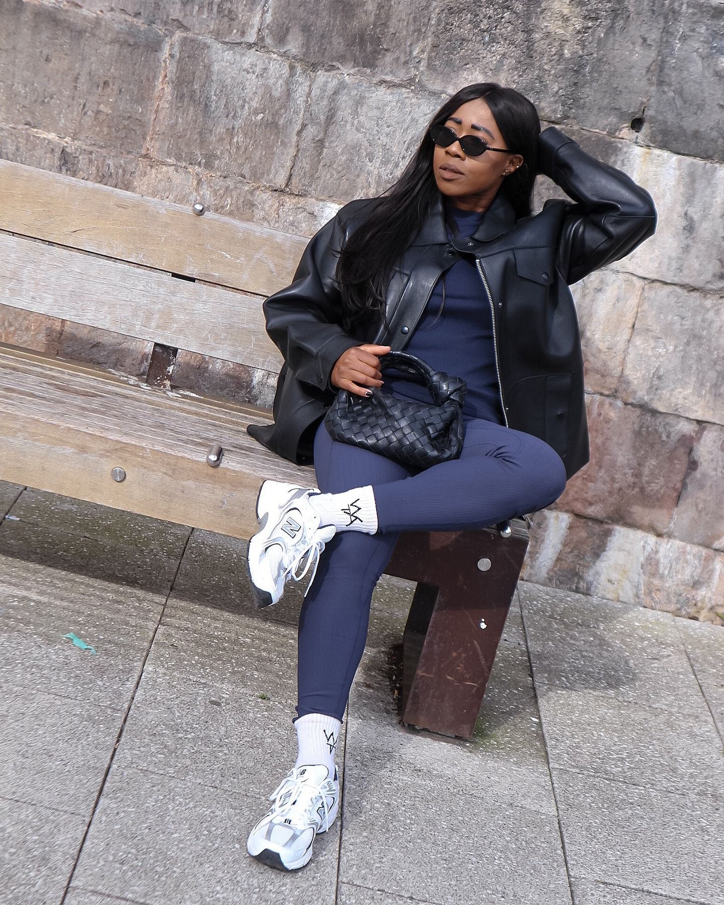 @_loissterling wears navy leggings with a navy knit and black leather jacket and white trainers.
