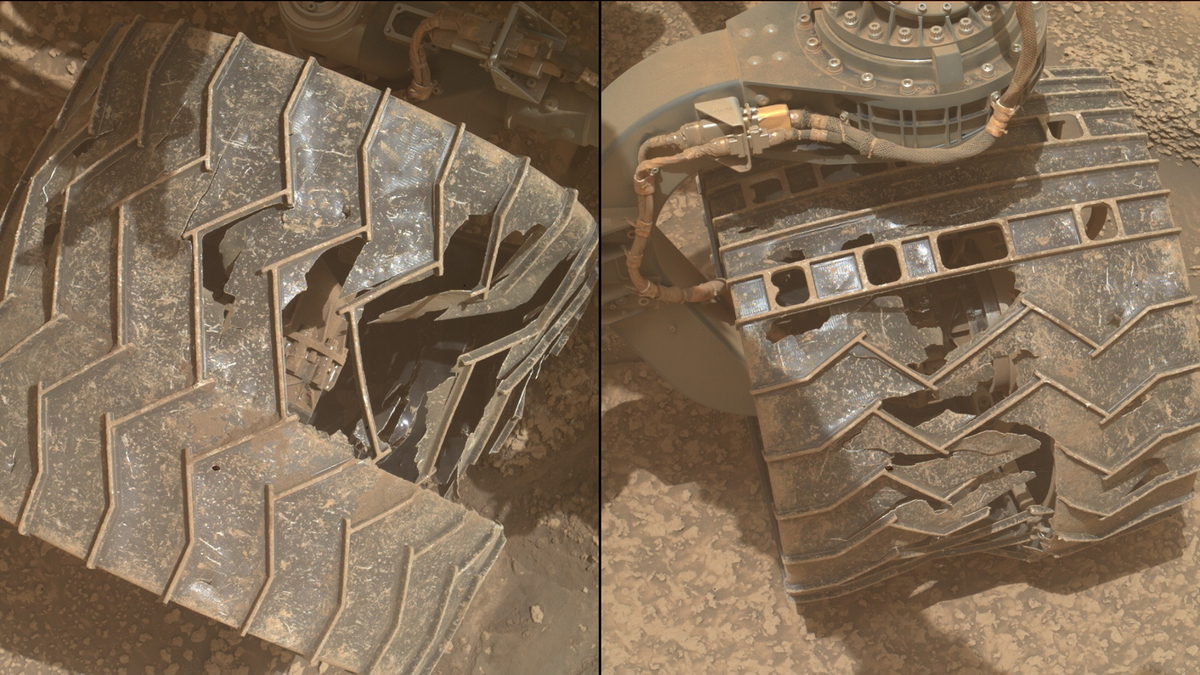 a close-up of a metal wheel with deep cracks and caved-in sections as it rests on a reddish-orange rocky surface