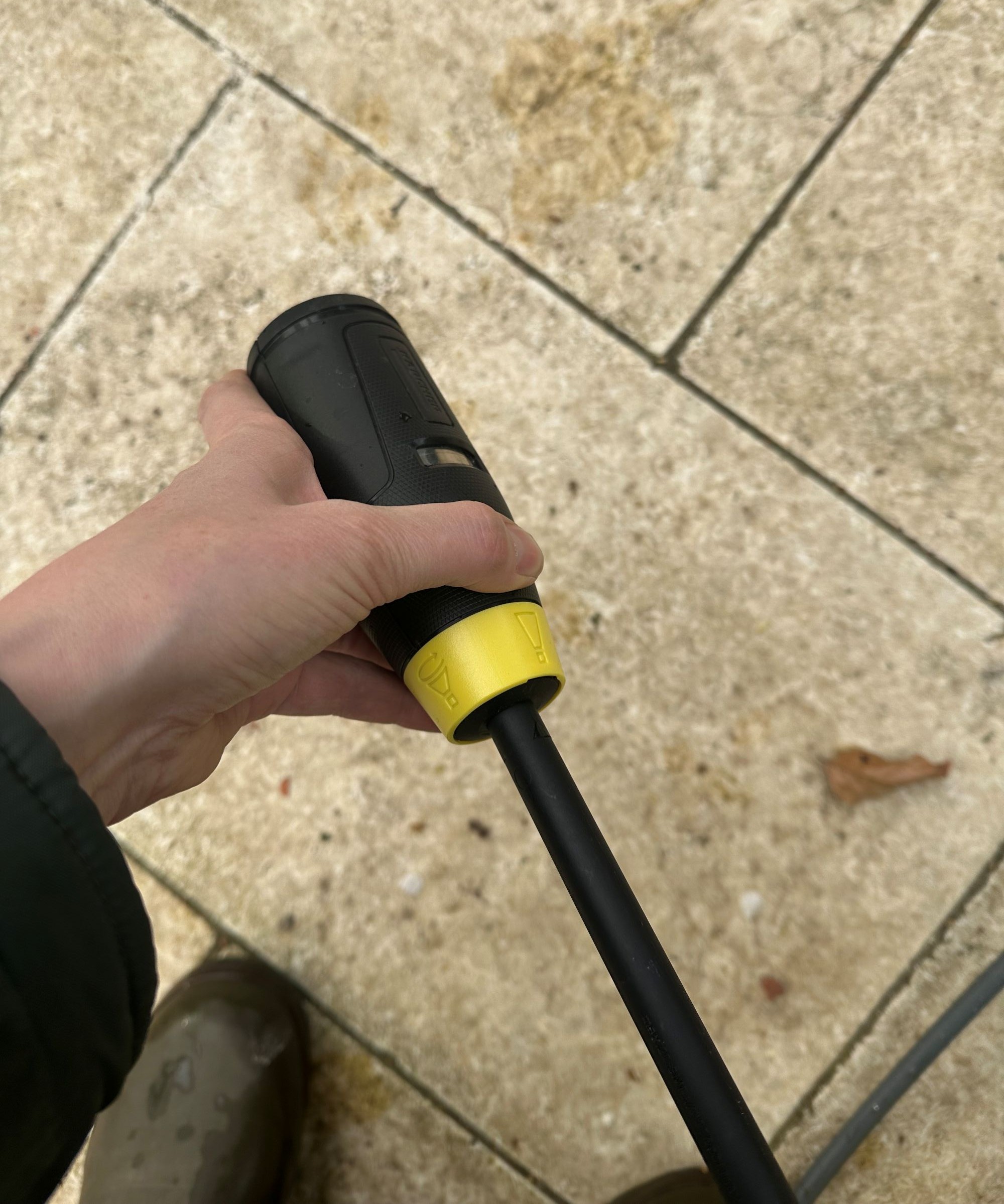 A yellow K&amp;auml;rcher K5 Comfort Premium pressure washer on a cream limestone patio