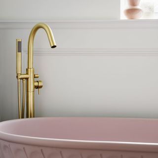 bathroom with white wall and fluted pink bathtub and brass tap