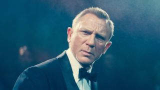 Daniel Craig dressed in a tuxedo stands in the middle of some mist with a confused look in No Time To Die.