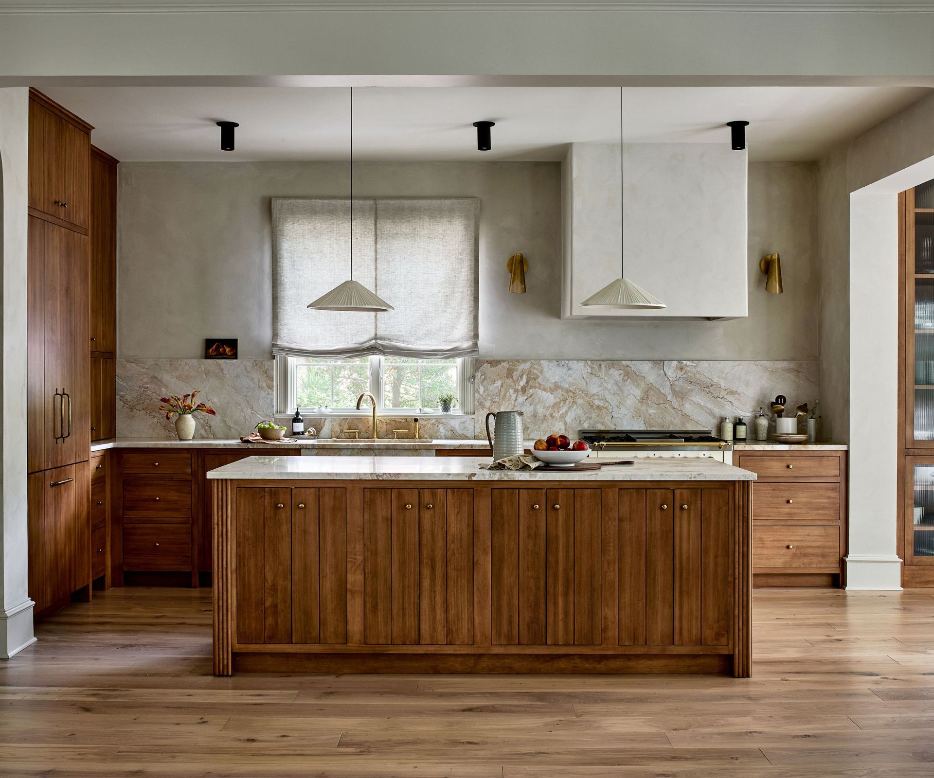 A Japandi-style kitchen with wooden cabinetry, marble countertops, limewash walls, and hardwood floors