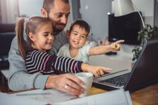 Two kids point to laptop computer as father looks on