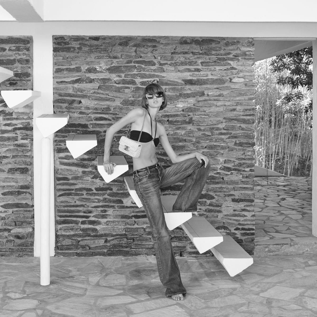 Woman in Celine shirt and bikini and sunglasses on stairs