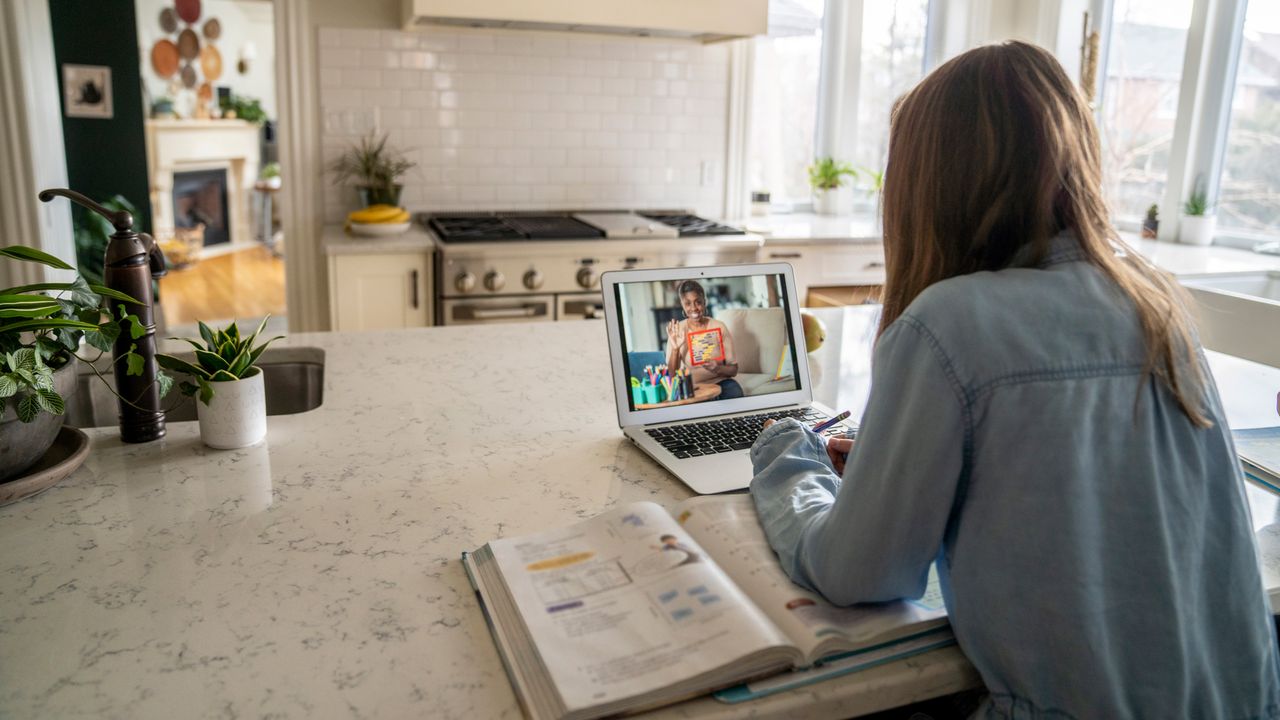 girl in a kitchen at a kitchen island on a laptop video call 