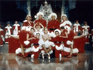 a stage production of dancers in red and white holiday outfits in White Christmas