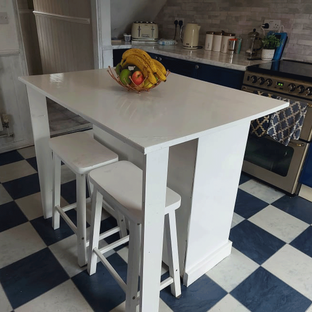 White kitchen island with two chairs on white and blue floor in front of oven