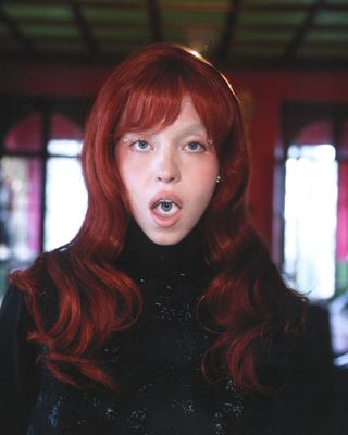 Sydney Sweeney in Who What Wear's April cover story wearing a red wig and black Miu Miu outfit.