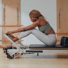 A woman on one of the best at-home Reformer Pilates machines