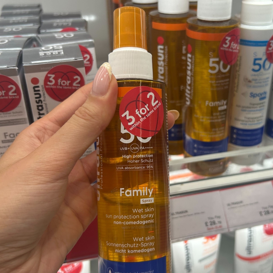 Hand holding bottle of Ultrasun Family Wet Skin Spray SPF50 in World Duty Free