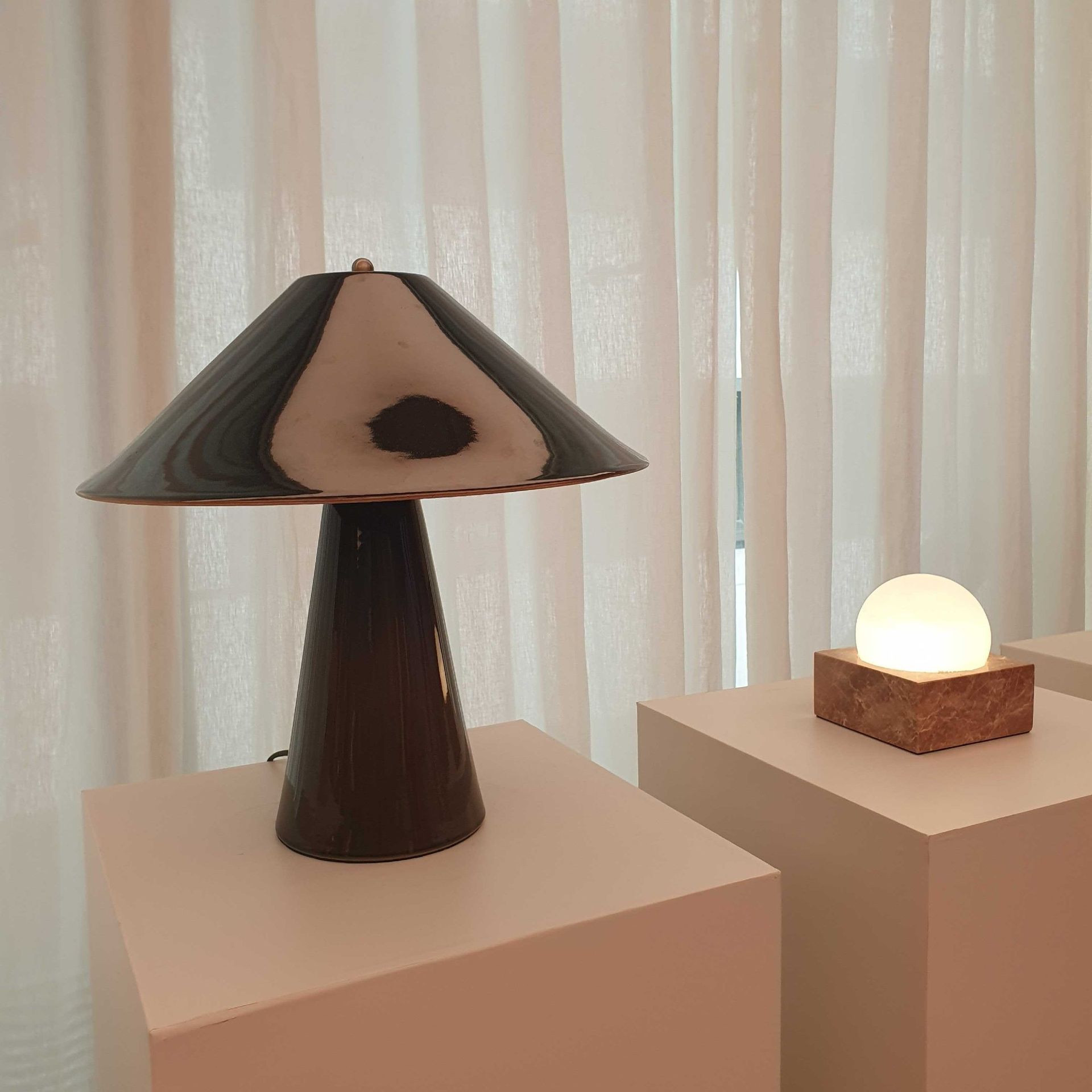 M&S ceramic table lamp in green on a white plinth next to an alabaster and marble lamp at the M&S autumn/winter 2026 press showcase