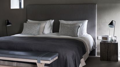 Dark grey bedroom with double bed with leather headboard and bench