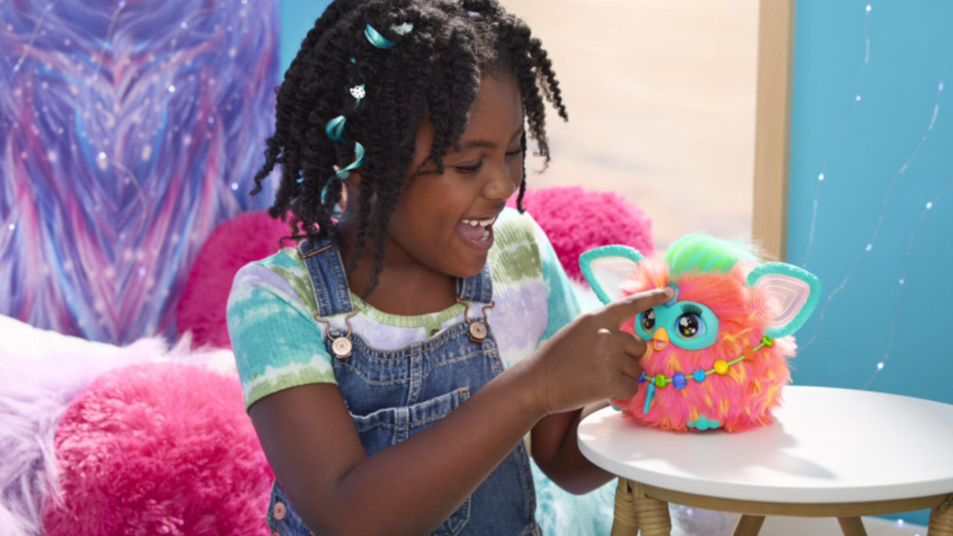 Ein kleines Mädchen drückt den herzförmigen Knopf an einem Furby-Spielzeug