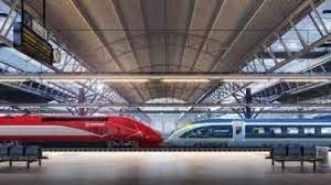 A blurred image of two Eurostar trains, one blue, one read, at a station.