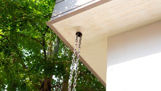 Rain chain suspended from underside of roof