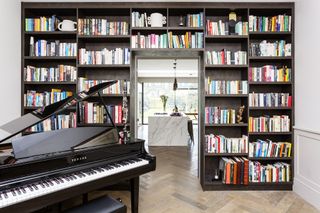 library/music room with grand piano, view into kitchen, herringbone floor, bookcases