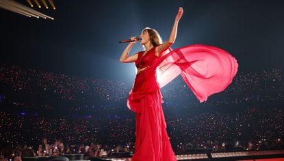 Taylor Swift performs at the Eras Tour in Cardiff, Wales, wearing a red alberta ferretti dress with a semi sheer cape and stomach cut-outs