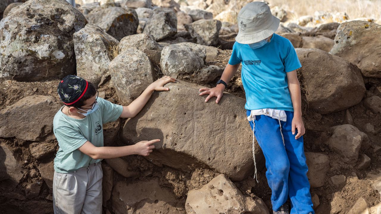 Local students point to a carving of two stick figures with horns, which may represent the cult of a Mesopotamian moon god.