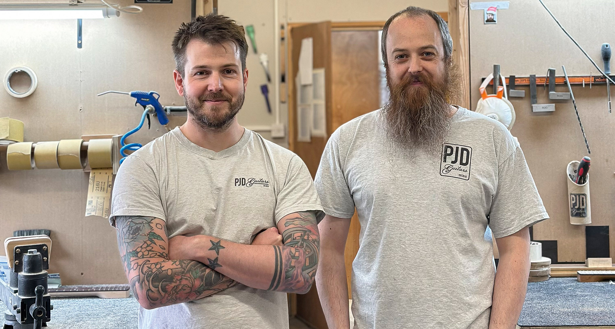 PJD Guitars founder Leigh Dovey [left] and custom shop luthier Josh Parkin photographed in the PJD workshop, both wearing regulation gray T-shirts.
