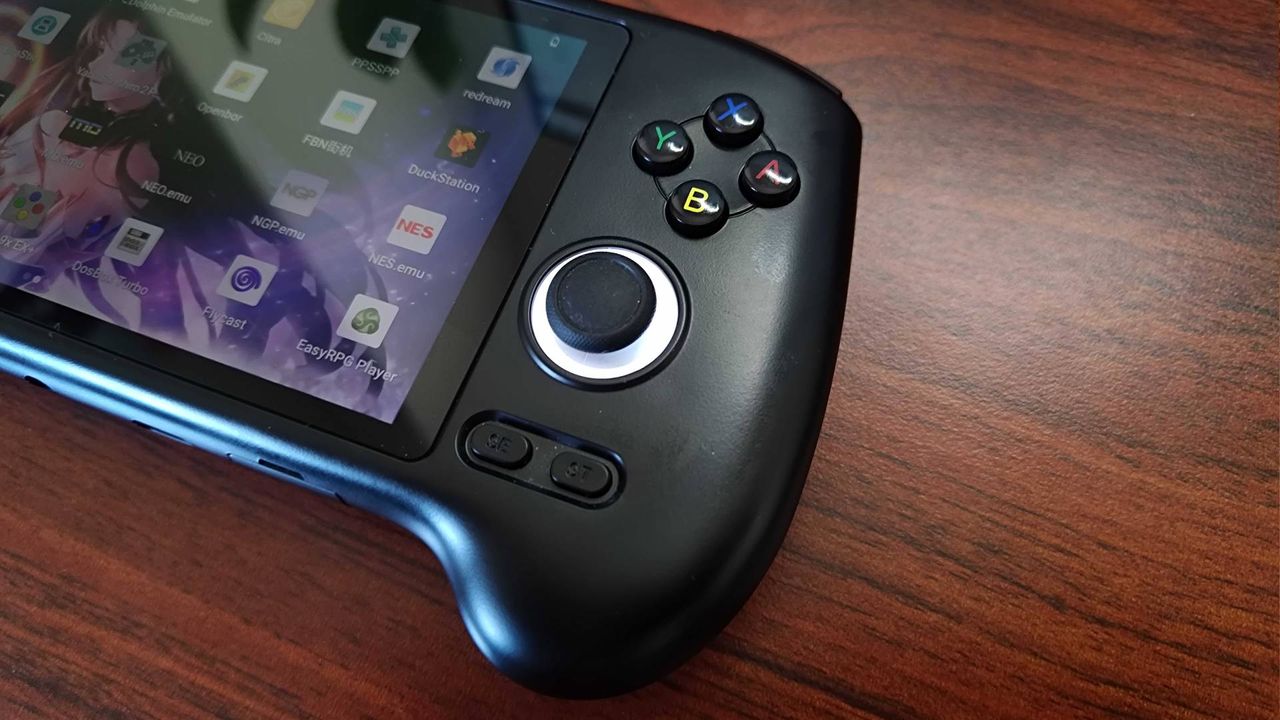 Close up of Anbernic RG556 thumbstick and buttons with handheld sitting on woodgrain desk.