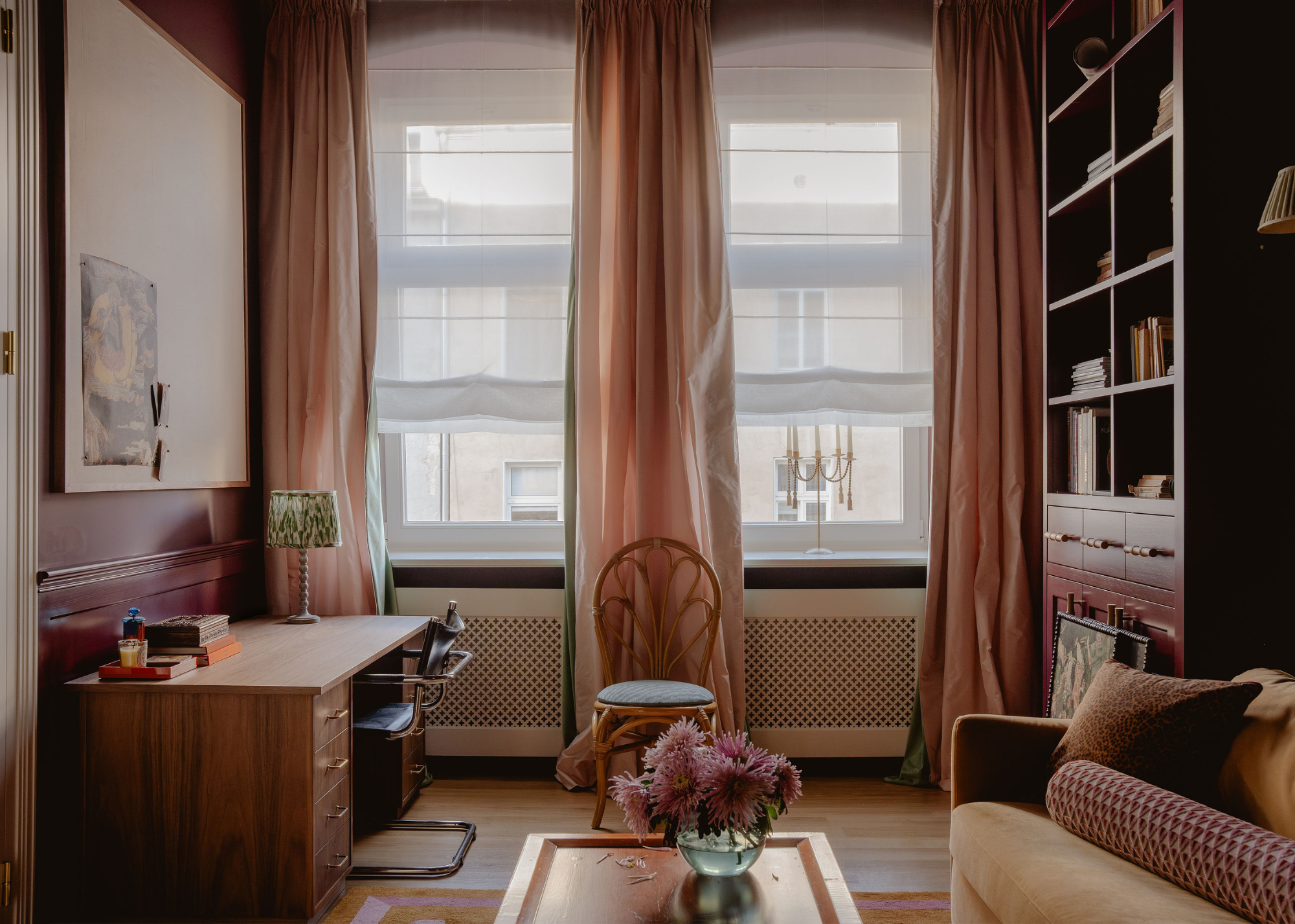 cozy study with dark plum walls, pink curtains and chic furniture throughout