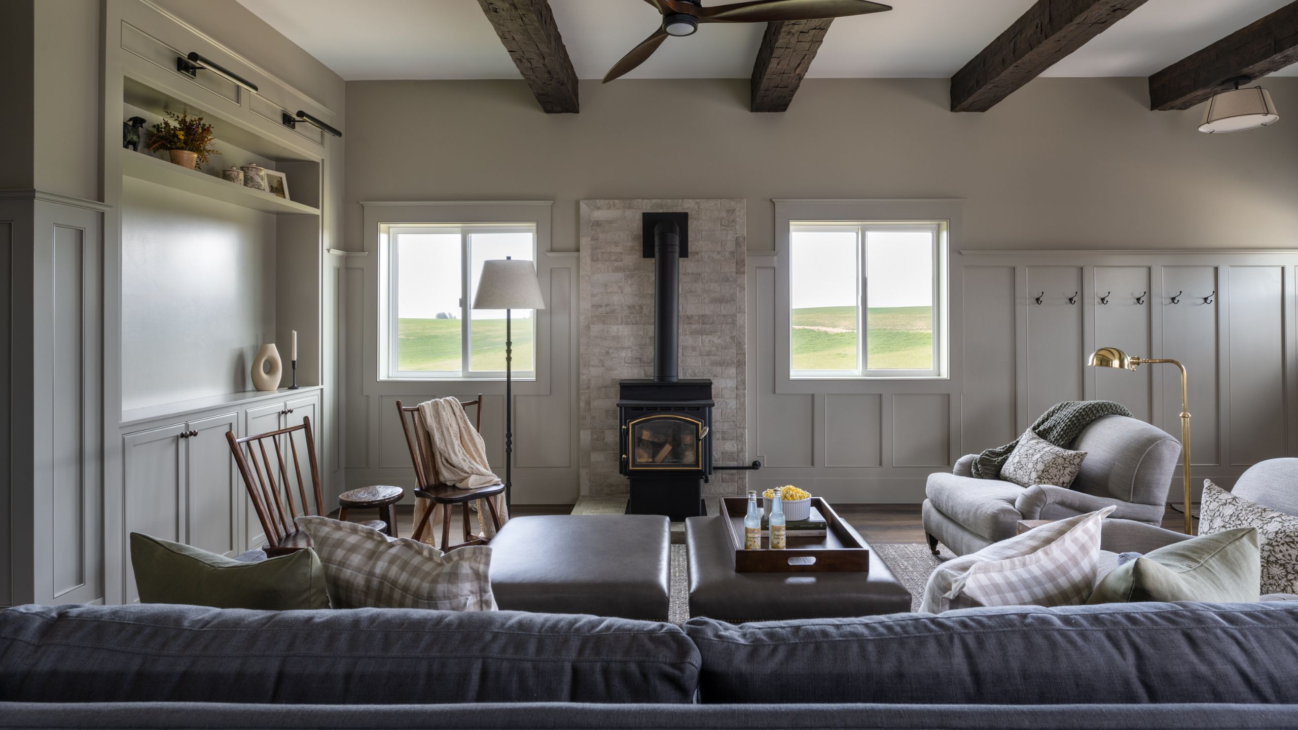 a neutral yet moody barn living area with log burning stove, ceiling beams and comfortable furniture