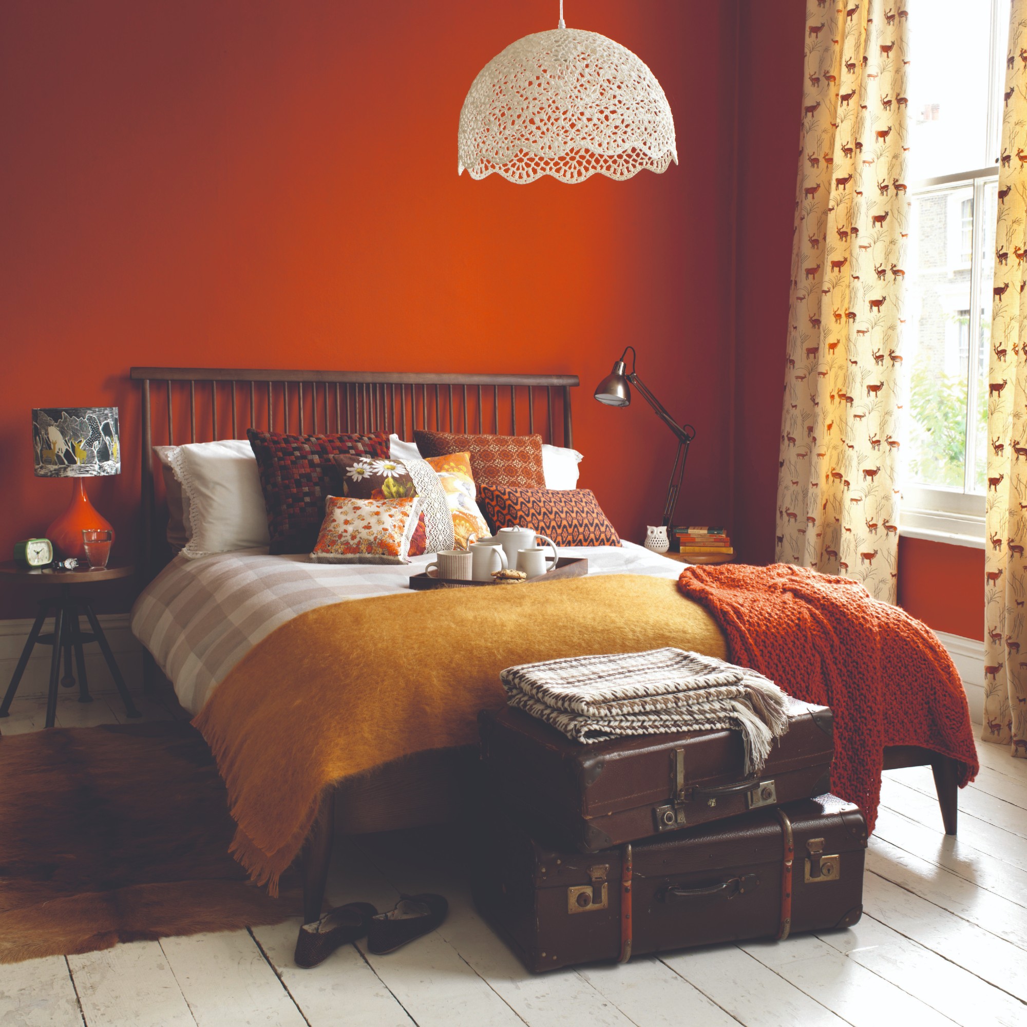 A bedroom painted in dark orange with white-painted wooden floors and dark wooden furniture