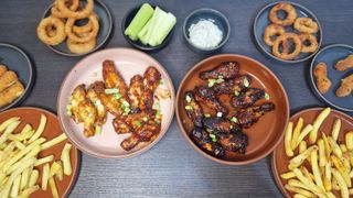 Two plates of chicken wings, the one on the left is significantly less browned than the plate on the right