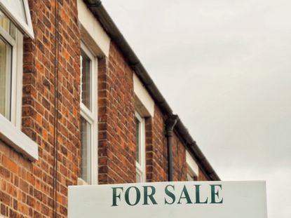 For sale sign outside brick terraced houses