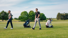 2 men walking on the golf course with the golf bags