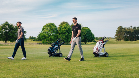 2 men walking on the golf course with the golf bags