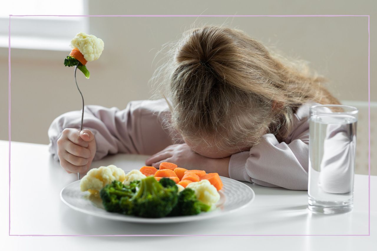 Child with head on the table in front of a plate of vegetables