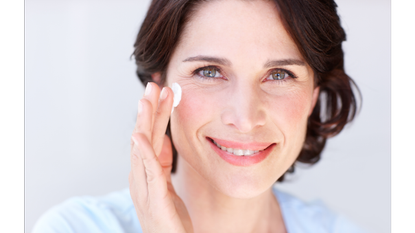 Woman smiling and demonstrating how to apply eye cream