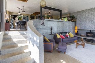 A cast concrete staircase curves down to the living space