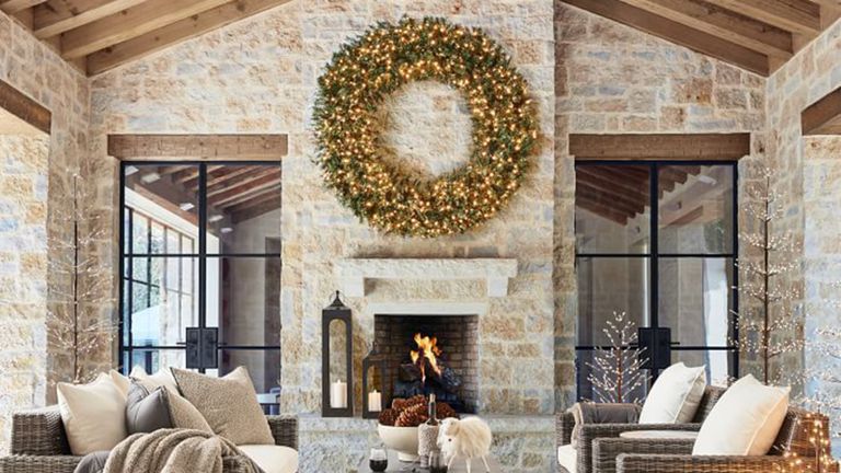 A rustic barn-style living room with oversized artificial lit Christmas wreath