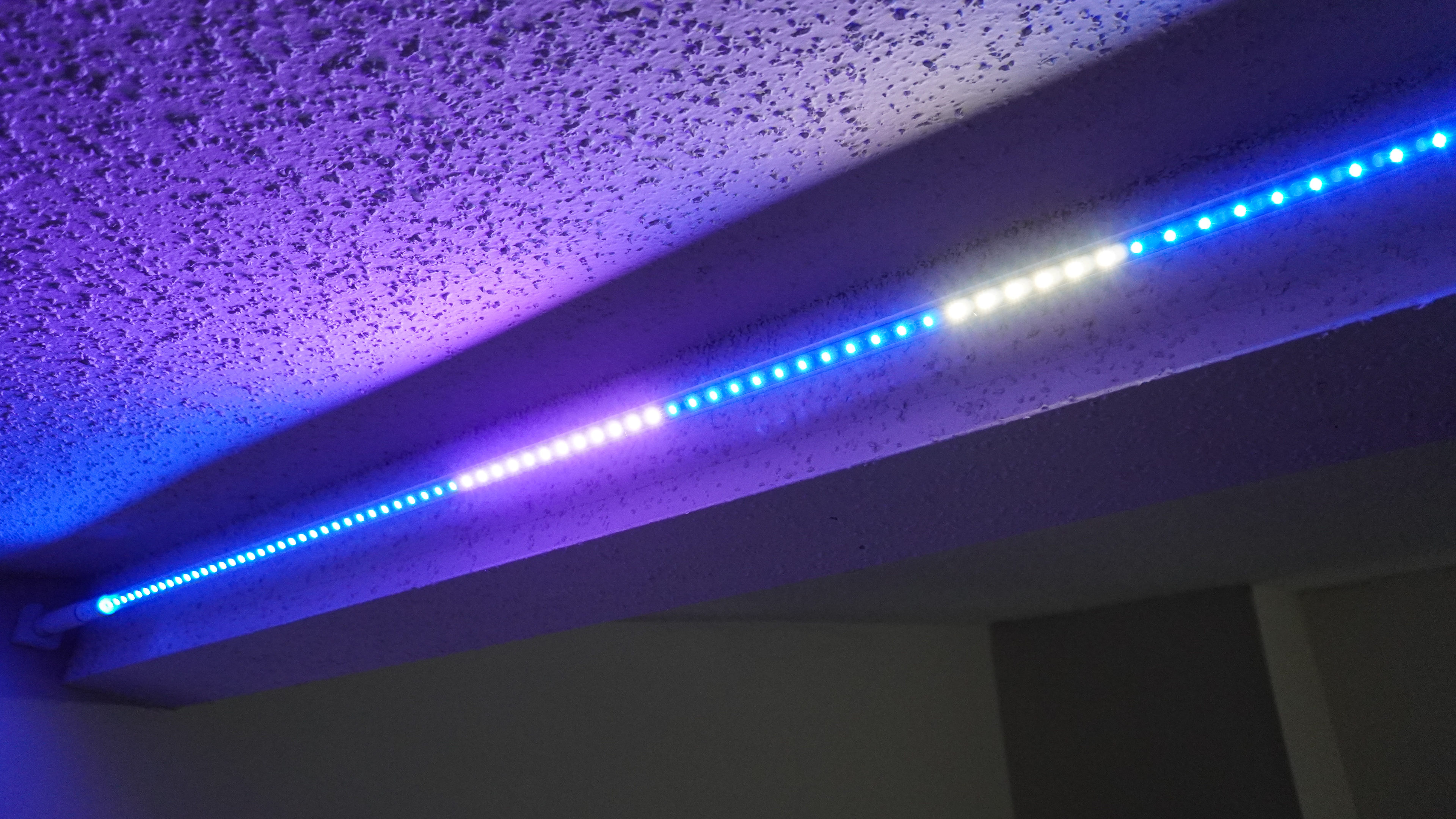 The Govee Strip Light with Skyline Kit mounted behind a beam with colored light emanating outward