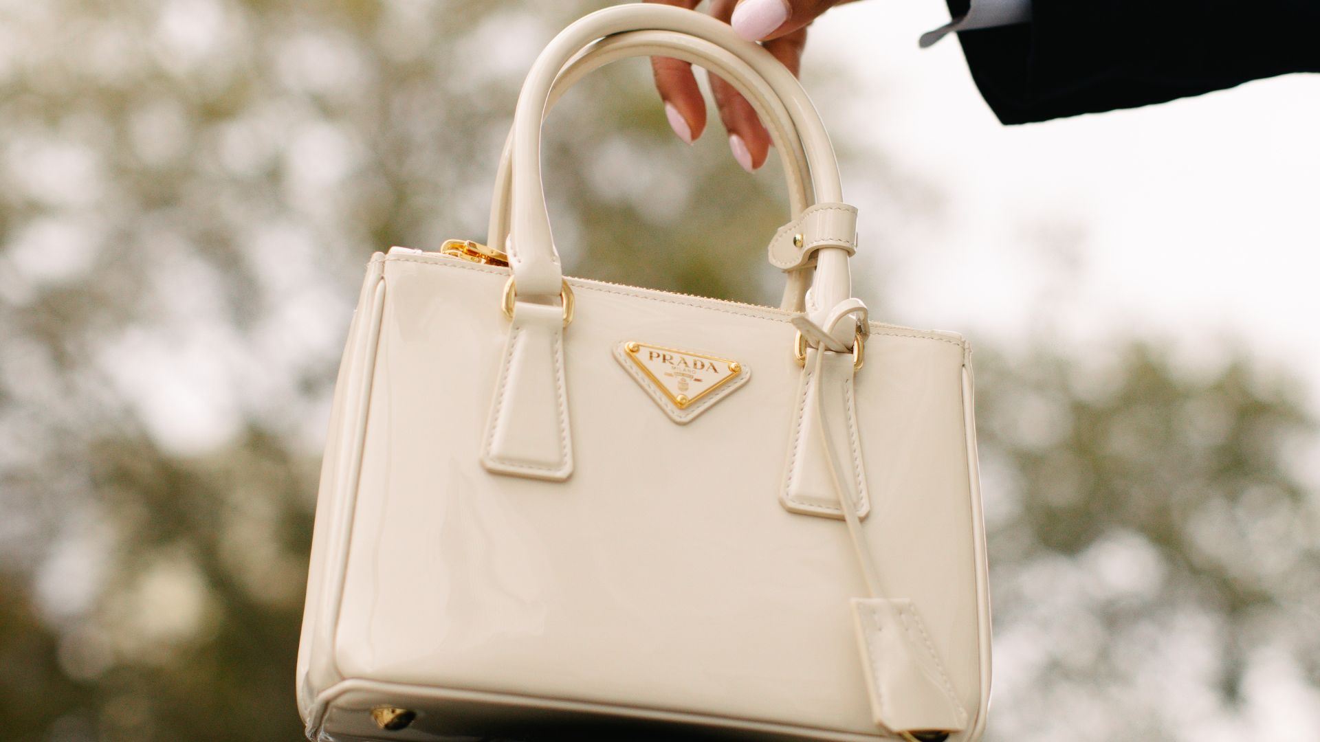 Woman reaches out for white Prada Galleria tote bag.