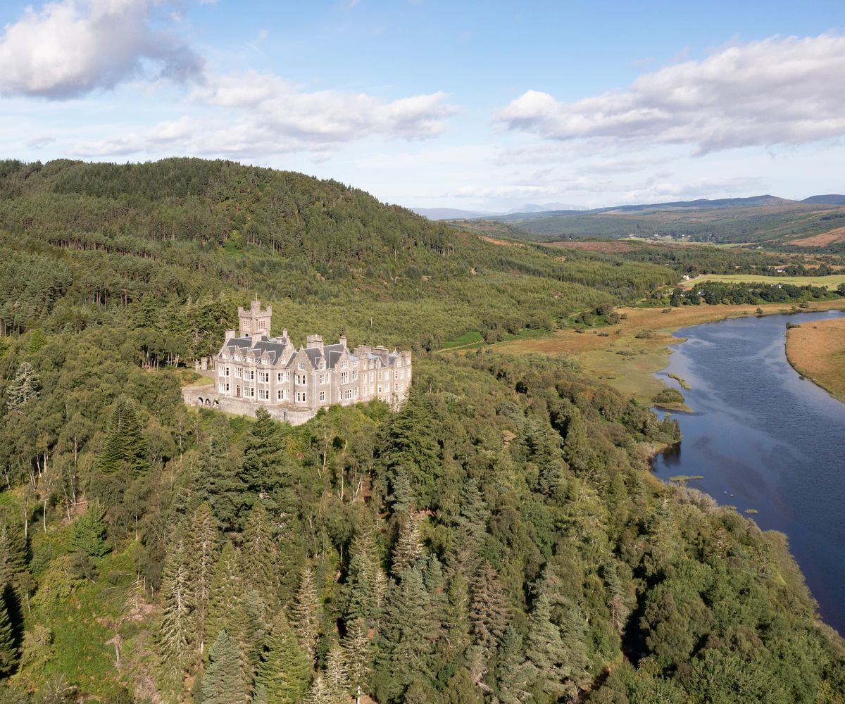 A castle overlooking a river surrounded by trees
