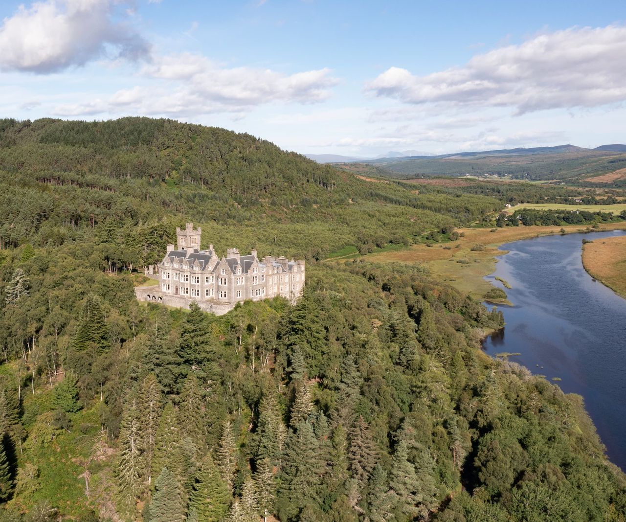 A castle overlooking a river surrounded by trees