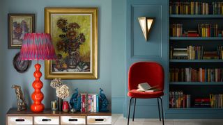 dark blue walls with bright orange lamp base and deep red chair in front