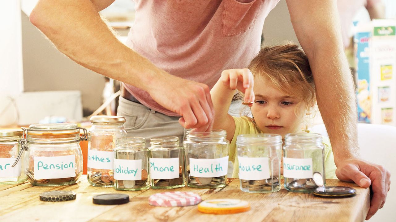 Young girl putting money into savings jars