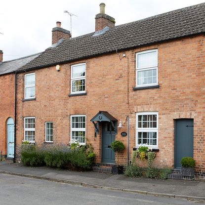 house with brick walls white windows and grey doors