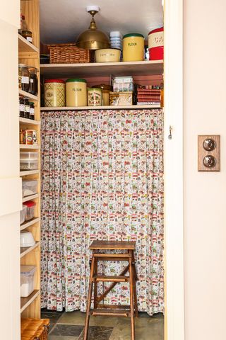 pantry filled with vintage tins and partly covered by a floral vintage curtain