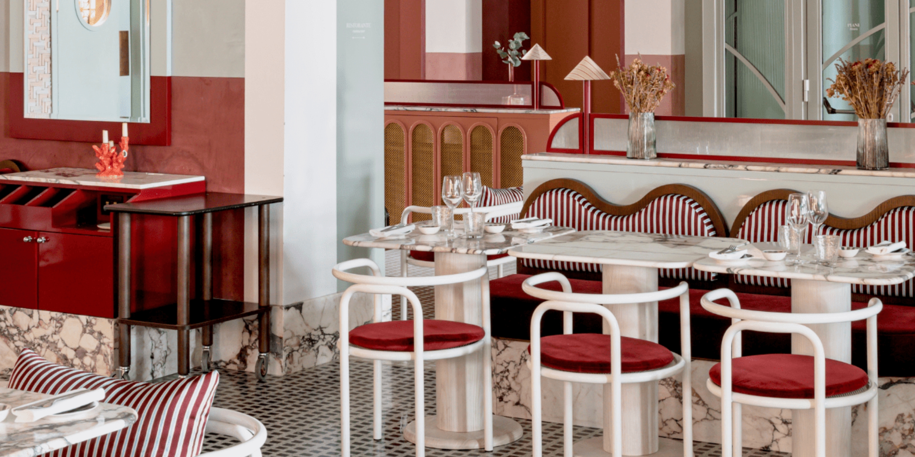 A red, white, and mint blue-hued restaurant boasts playful French decor across plush stripy textiles, whimsical forms, and eye-catching patterns.