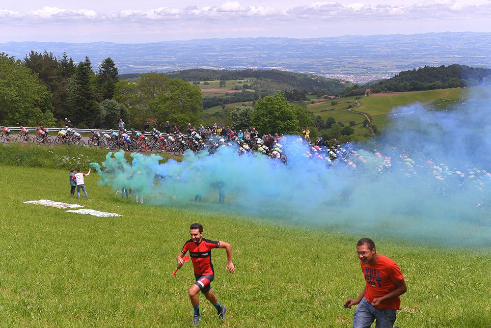 Fans run from the smoke show along the route during stage 2 at Dauphine