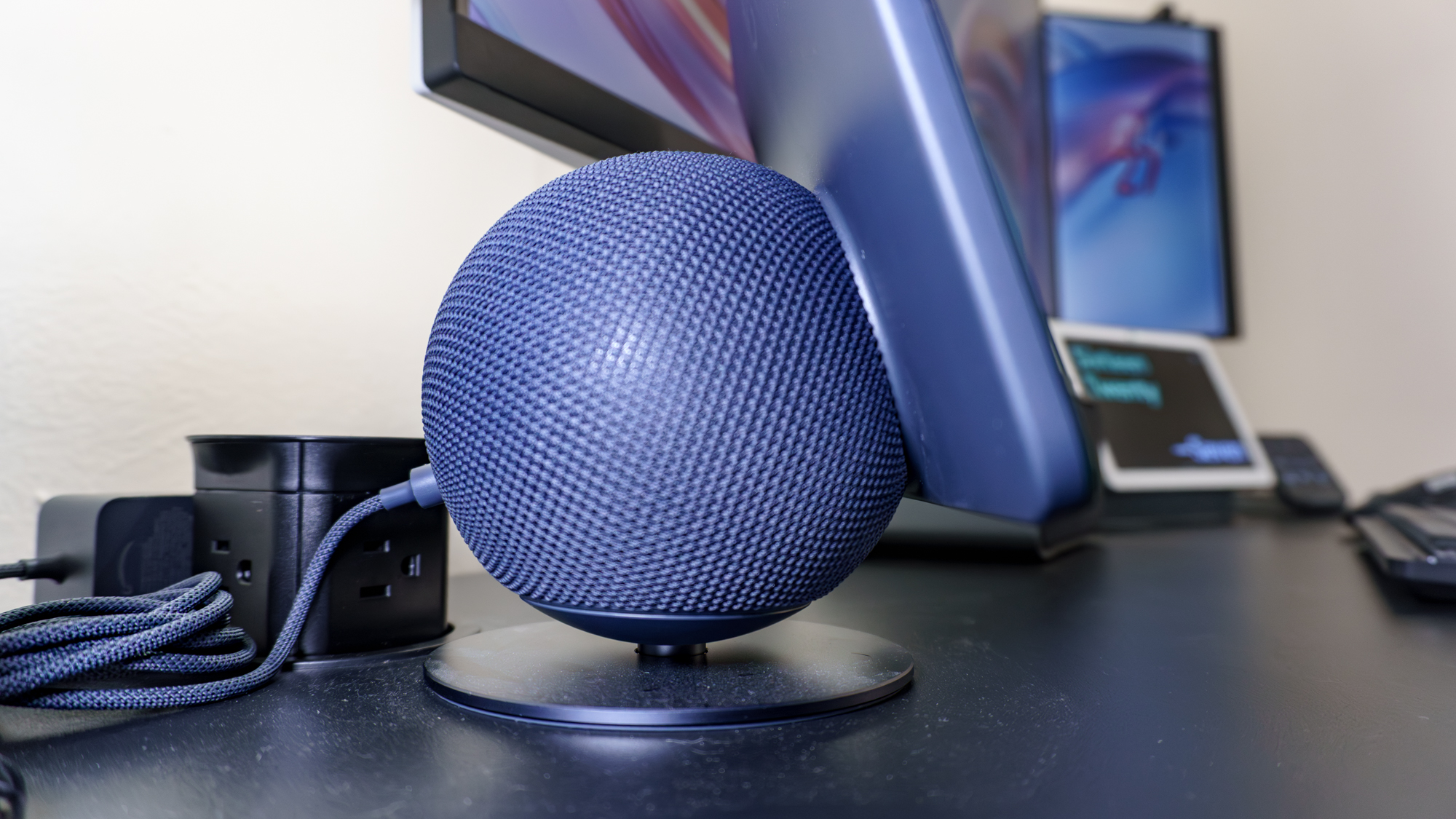 The Echo Show 11 plugged into a pop-up power grommet on the side of the Uplift V3 standing desk